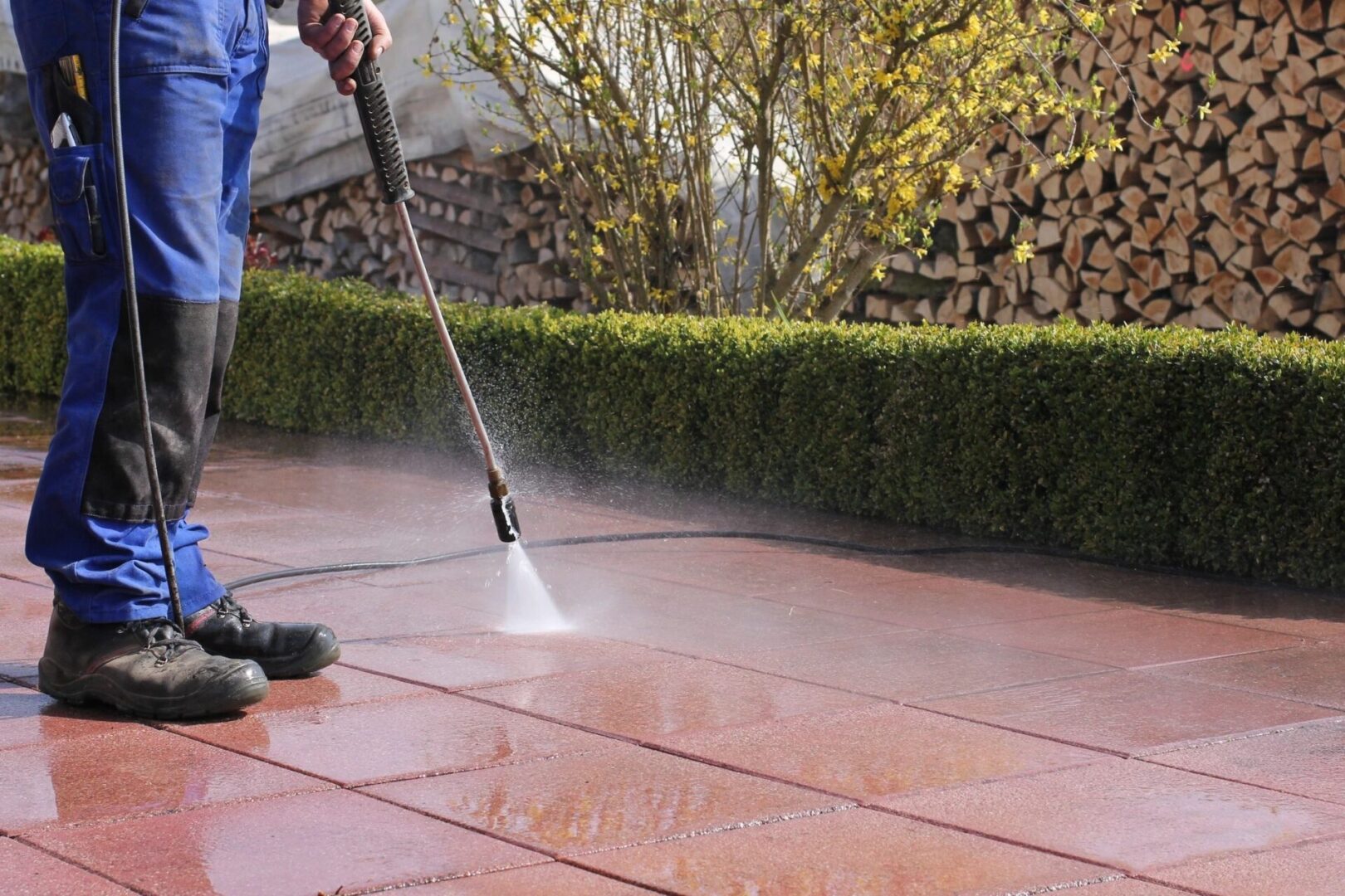 A person using a power washer on the patio.